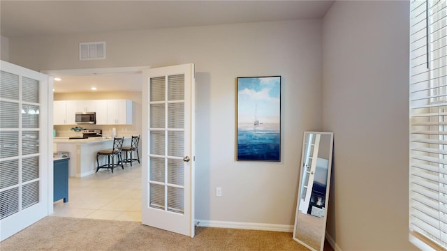 interior space featuring light carpet, light tile patterned flooring, visible vents, and baseboards