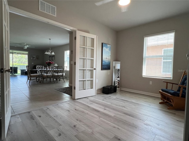 living area featuring light wood-type flooring, visible vents, ceiling fan, and baseboards