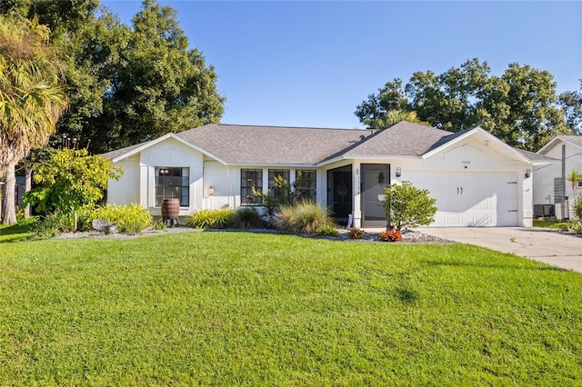 ranch-style home featuring a garage, a front lawn, and central air condition unit