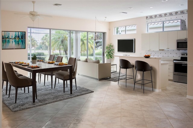 tiled dining area with ceiling fan and plenty of natural light