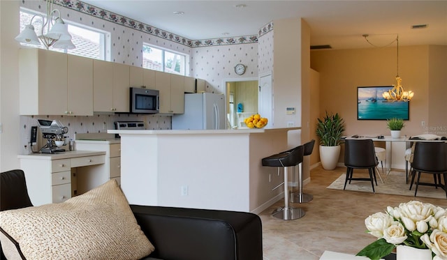 kitchen featuring a notable chandelier, white cabinetry, kitchen peninsula, white fridge, and decorative light fixtures