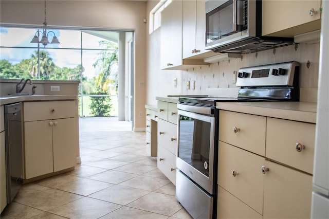 kitchen with appliances with stainless steel finishes, light tile patterned floors, sink, and pendant lighting