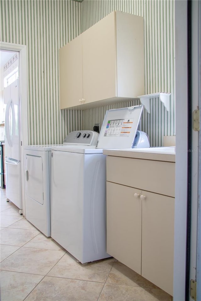 washroom featuring washer and clothes dryer, cabinets, and light tile patterned floors