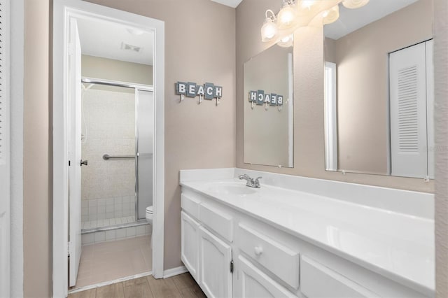 bathroom featuring toilet, an enclosed shower, wood-type flooring, and vanity