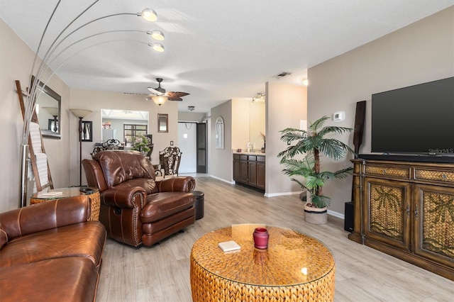 living room with light wood finished floors, baseboards, visible vents, and a ceiling fan