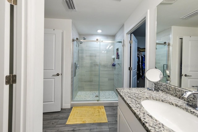 bathroom featuring wood-type flooring, an enclosed shower, and vanity