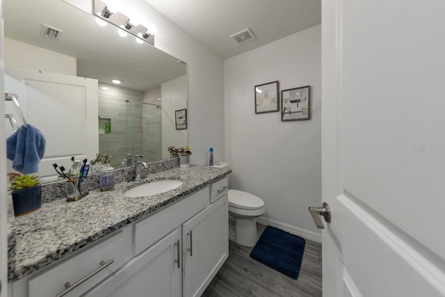 bathroom featuring vanity, wood-type flooring, a shower with shower door, and toilet