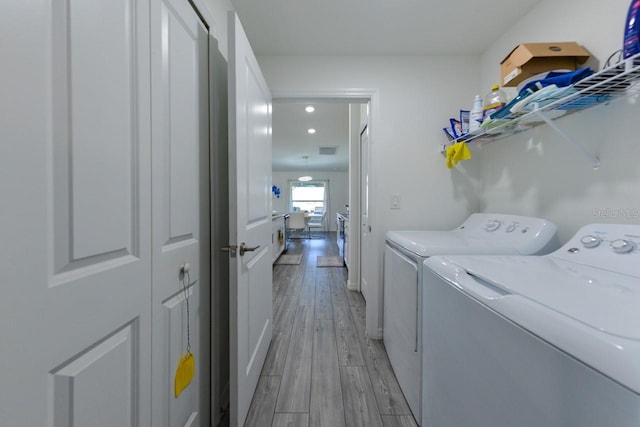 clothes washing area featuring light hardwood / wood-style floors and independent washer and dryer