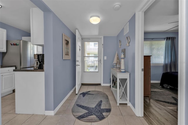 foyer featuring light tile patterned flooring, baseboards, and visible vents