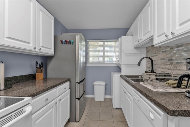 kitchen featuring tasteful backsplash, dishwasher, light tile patterned floors, dark countertops, and white cabinets