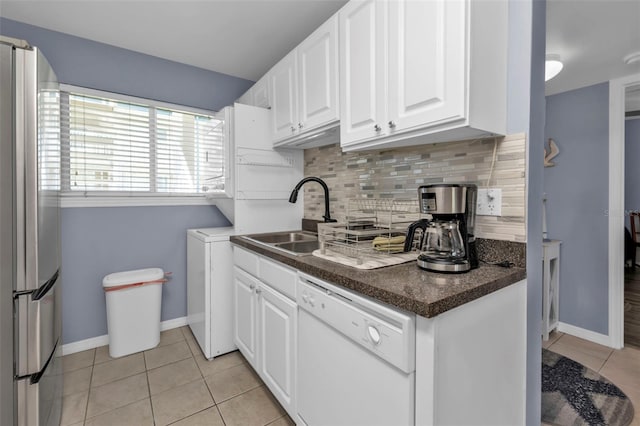 kitchen with light tile patterned flooring, tasteful backsplash, white cabinets, white dishwasher, and sink