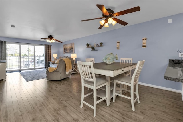 dining room featuring baseboards, wood finished floors, and ceiling fan