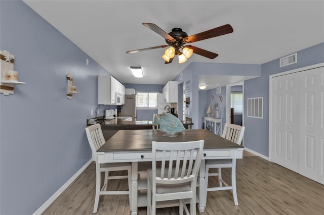 dining room featuring baseboards, ceiling fan, visible vents, and light wood-style floors