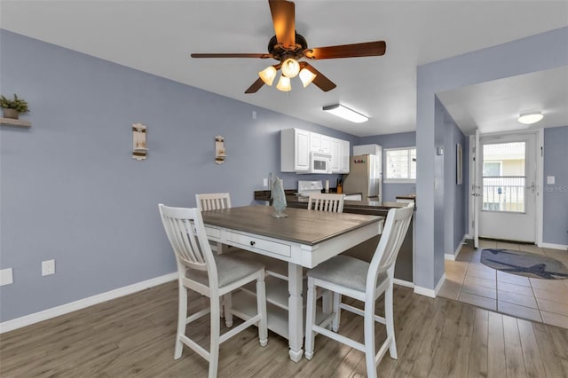 dining area with light wood-type flooring and ceiling fan