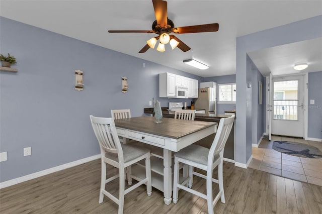 dining room with baseboards, light wood-style floors, and a ceiling fan