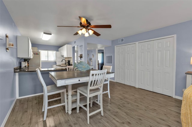 dining room featuring hardwood / wood-style floors, ceiling fan, and sink