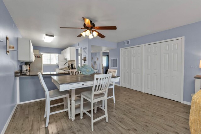 dining room with baseboards, light wood-type flooring, visible vents, and ceiling fan