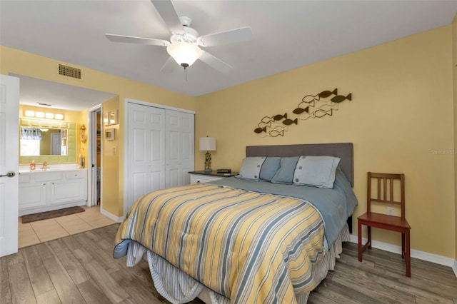 bedroom with a closet, ceiling fan, light hardwood / wood-style flooring, ensuite bathroom, and sink