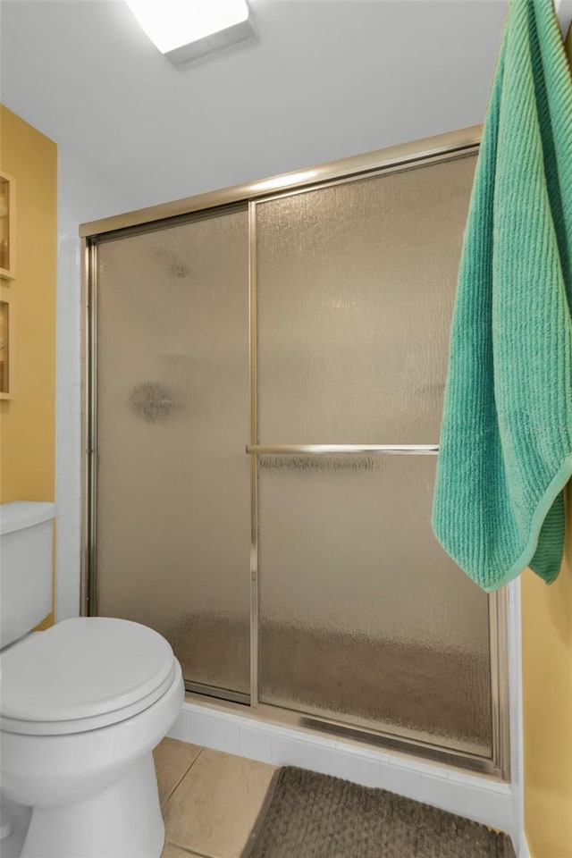 bathroom with toilet, an enclosed shower, and tile patterned floors