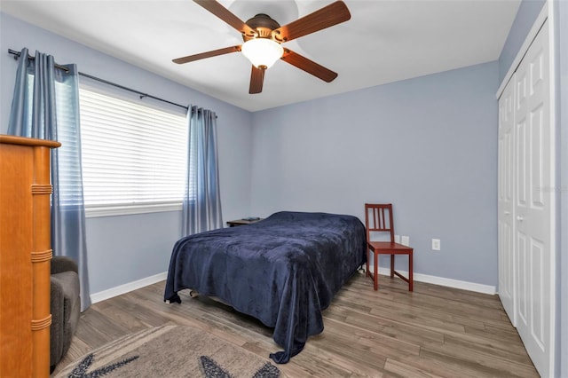 bedroom featuring a closet, baseboards, ceiling fan, and wood finished floors