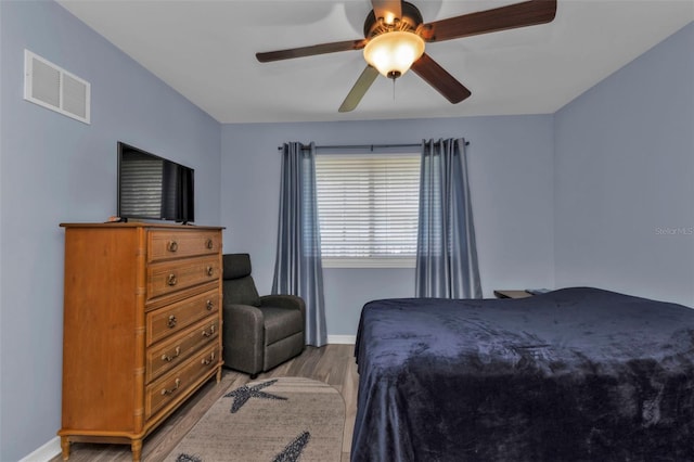bedroom with baseboards, a ceiling fan, visible vents, and light wood-type flooring