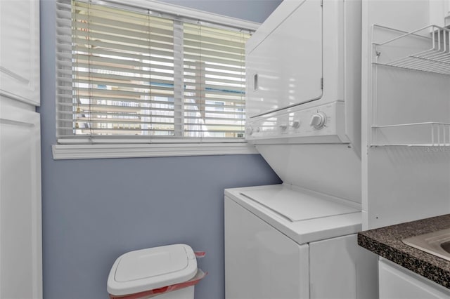 clothes washing area with stacked washing maching and dryer and laundry area