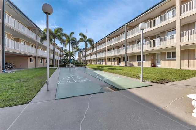 view of home's community with a lawn and shuffleboard