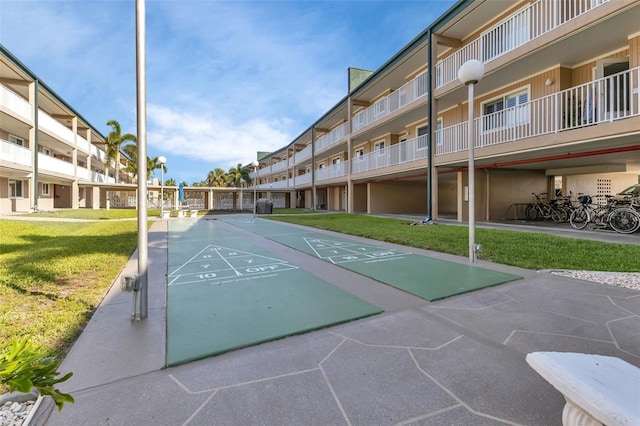 view of property's community featuring a lawn and shuffleboard