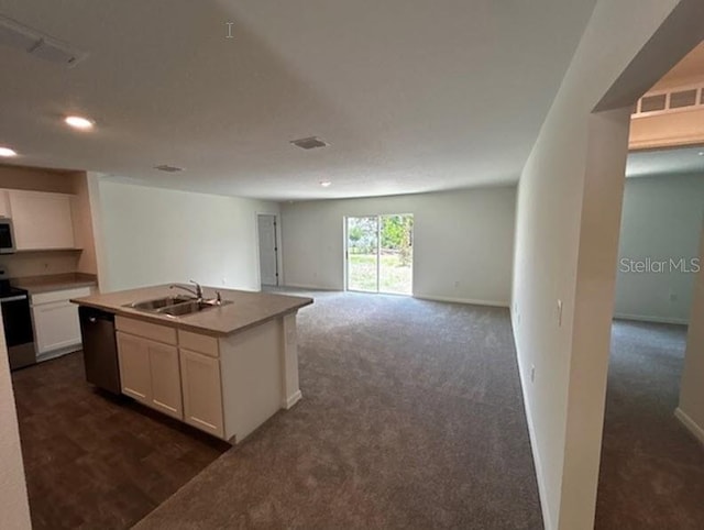 kitchen featuring white cabinets, stainless steel appliances, dark colored carpet, a center island with sink, and sink