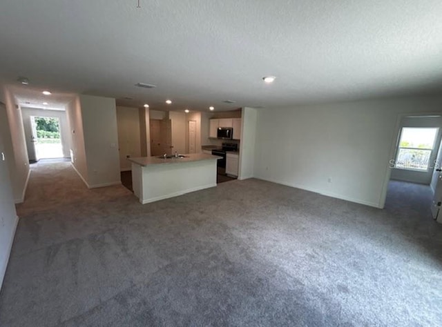 unfurnished living room featuring a textured ceiling, sink, and carpet flooring