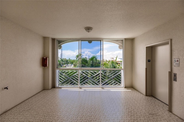 spare room featuring a textured ceiling and elevator