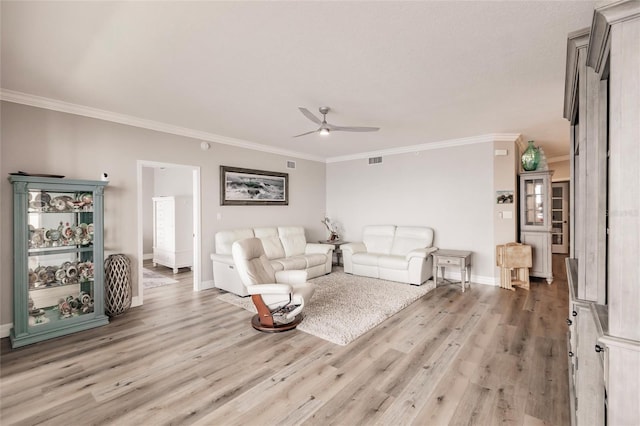 living area featuring crown molding, a ceiling fan, light wood finished floors, baseboards, and visible vents