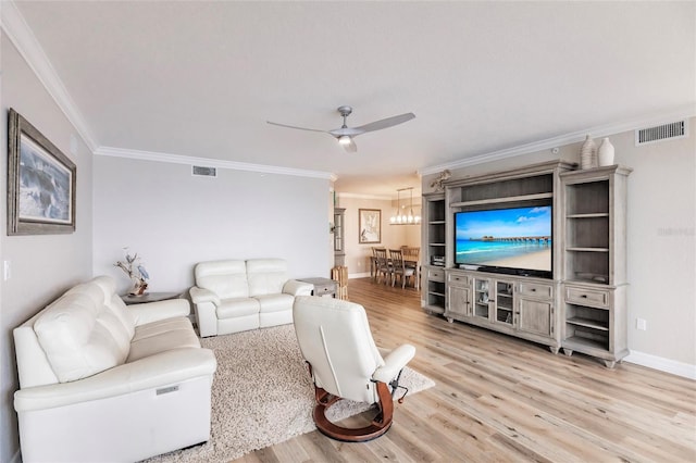 living room featuring light wood-style flooring, visible vents, a ceiling fan, and ornamental molding