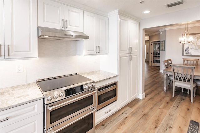 kitchen featuring white cabinets, stainless steel appliances, light hardwood / wood-style flooring, decorative light fixtures, and a chandelier