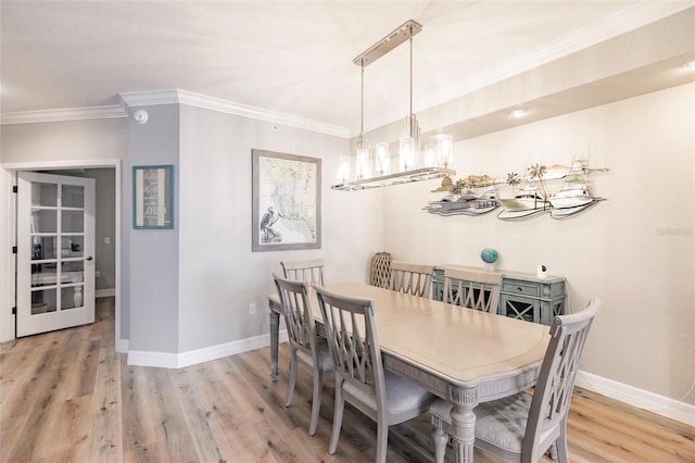 dining space with an inviting chandelier, ornamental molding, baseboards, and wood finished floors