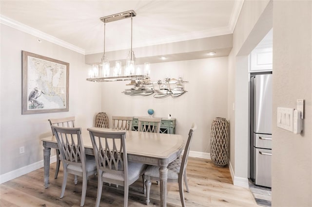 dining room with light wood finished floors, ornamental molding, baseboards, and a notable chandelier