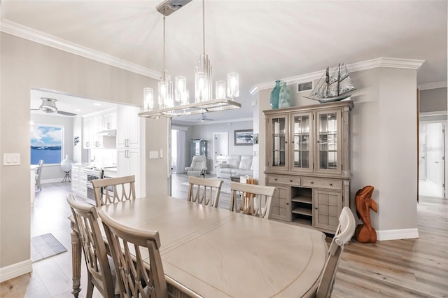 dining room with baseboards, light wood-style floors, crown molding, and ceiling fan with notable chandelier
