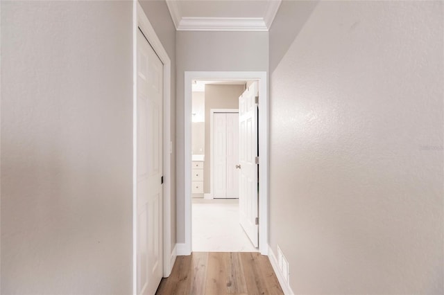 corridor with light hardwood / wood-style flooring and ornamental molding