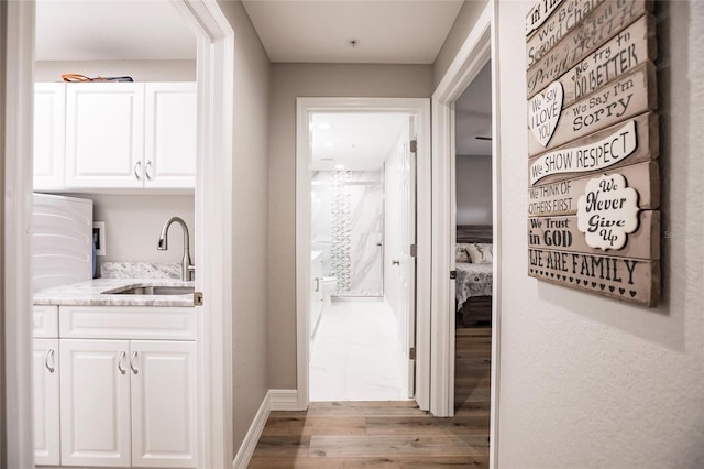 hall featuring a sink, baseboards, and wood finished floors