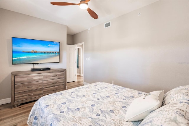 bedroom with baseboards, visible vents, wood finished floors, and a ceiling fan