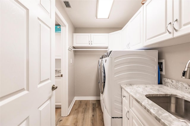 laundry room with a sink, visible vents, light wood-style flooring, cabinet space, and washing machine and dryer
