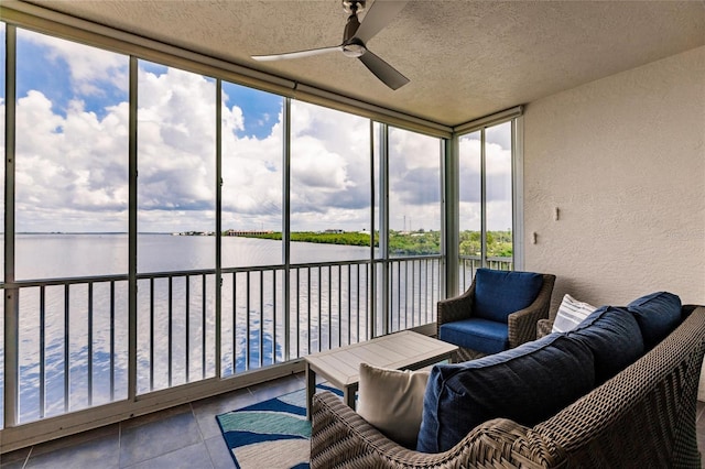 sunroom with a ceiling fan and a water view