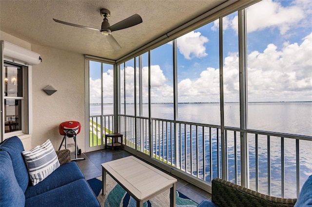 sunroom featuring tile patterned floors, a water view, a textured wall, and a textured ceiling
