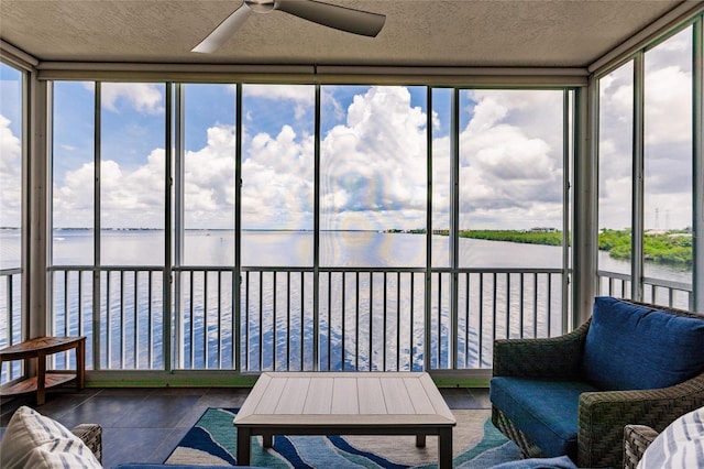 sunroom featuring floor to ceiling windows, tile patterned flooring, a water view, and a textured ceiling