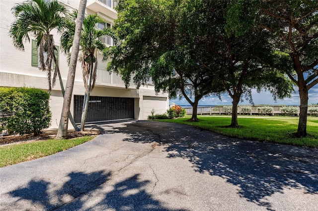 view of front of home with a front yard, a balcony, and a garage