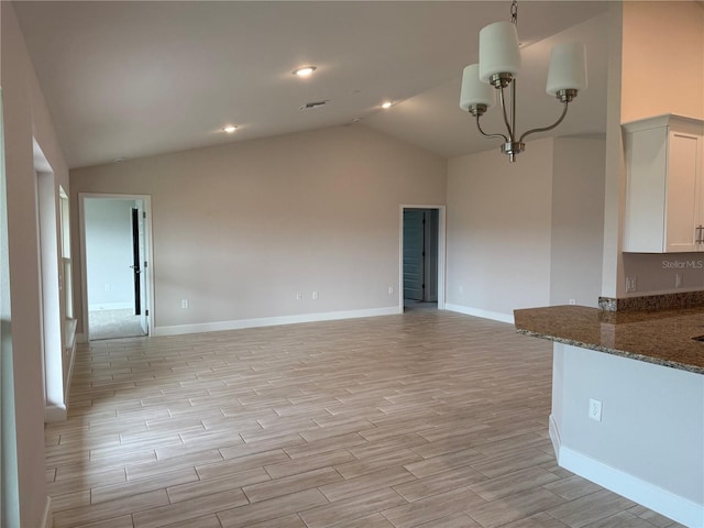 unfurnished living room featuring visible vents, baseboards, wood tiled floor, vaulted ceiling, and a chandelier