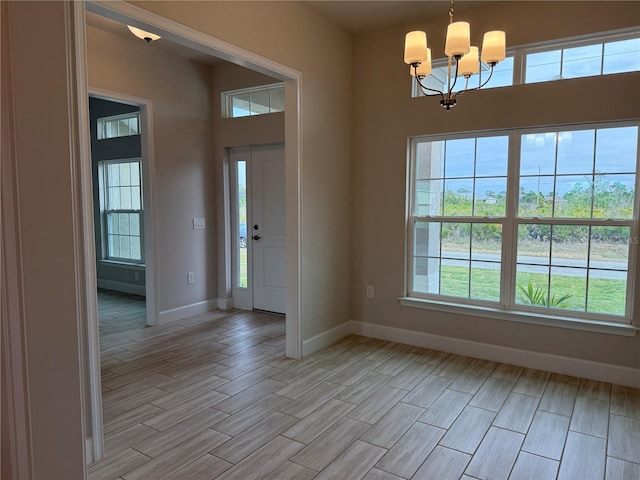 foyer entrance featuring light wood finished floors, baseboards, and an inviting chandelier