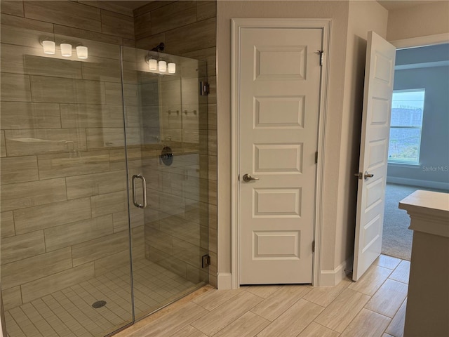 bathroom featuring a stall shower, wood finish floors, and baseboards