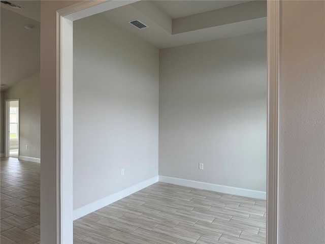 empty room with visible vents, light wood-style flooring, and baseboards