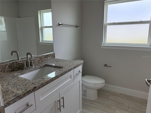 bathroom with toilet, baseboards, and vanity